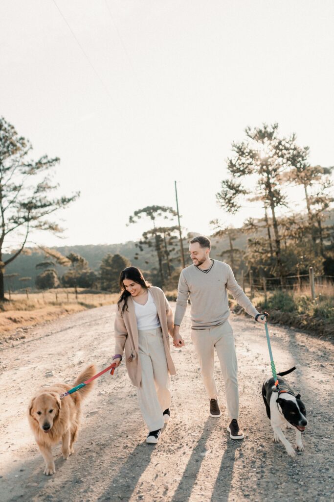 A couple walking their dogs on a dirt road